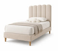 Cama individual tapizada beige con cabecera de paneles y patas de madera